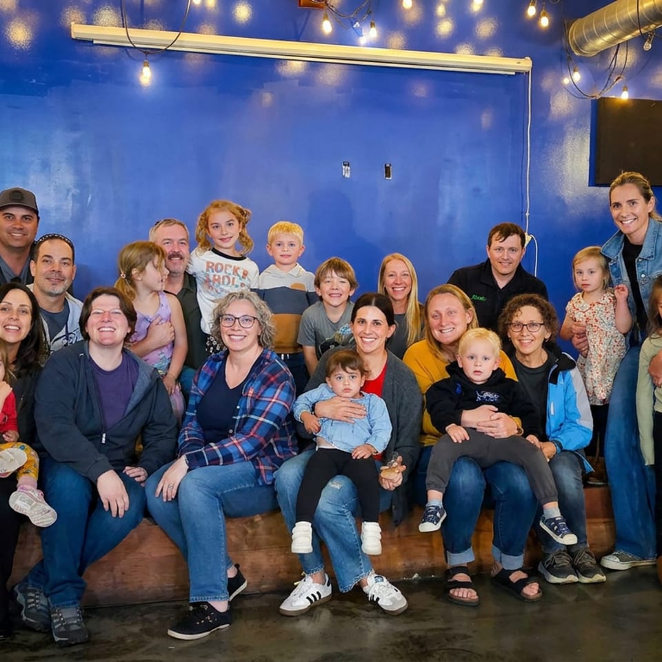 Large multigenerational group posing together inside a lively restaurant with blue walls and hanging string lights.